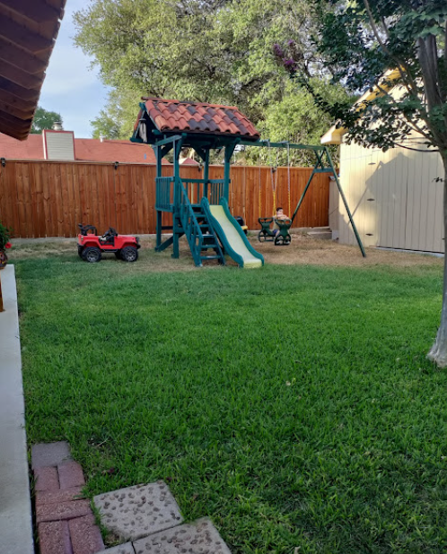 Outdoor playground with swing set and slide on a green lawn